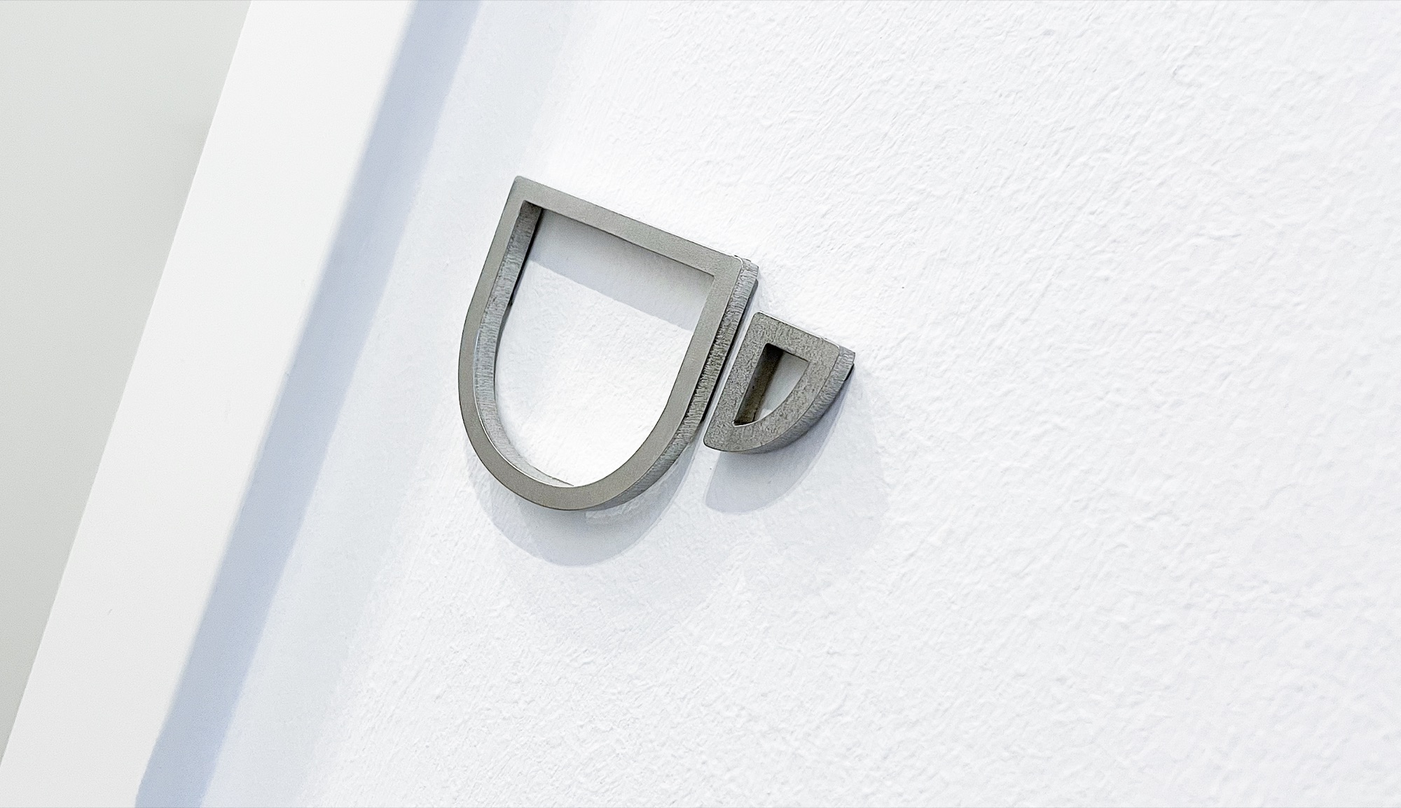 Detail: Wandzeichen aus Metall an heller Wand